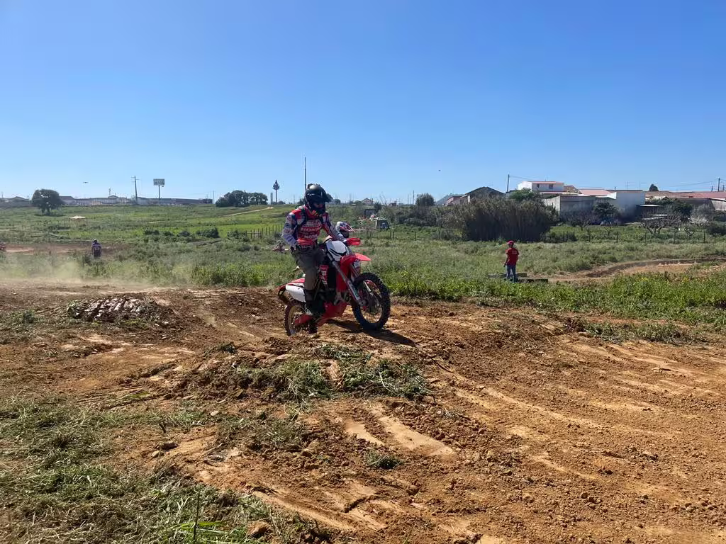 Enduro rider navigates dirt track under clear blue sky in Carregado, Lisbon, showcasing thrilling 3-hour adventure.