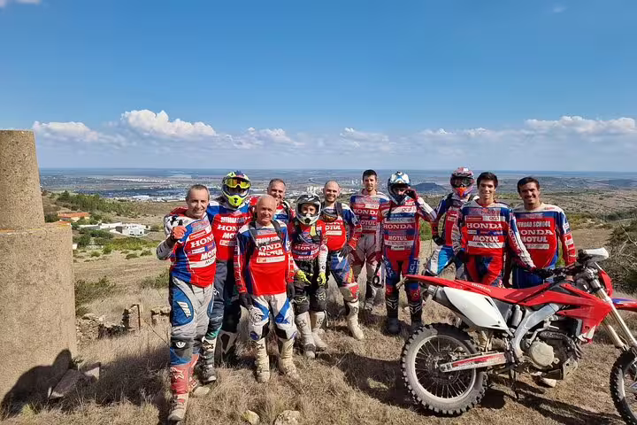 Group of enduro riders pose with bikes on Lisbon hilltop, showcasing adventure and camaraderie.