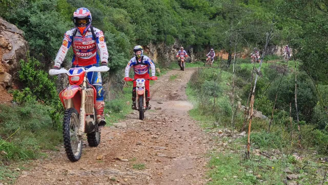 Riders navigate a rugged trail on dirt bikes during a 3-hour Enduro Tour in Carregado, Lisbon, surrounded by lush greenery.