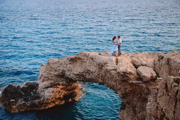 Engaged couple posing on a stunning rock formation over the sea in Ayia Napa, captured by a professional photographer.