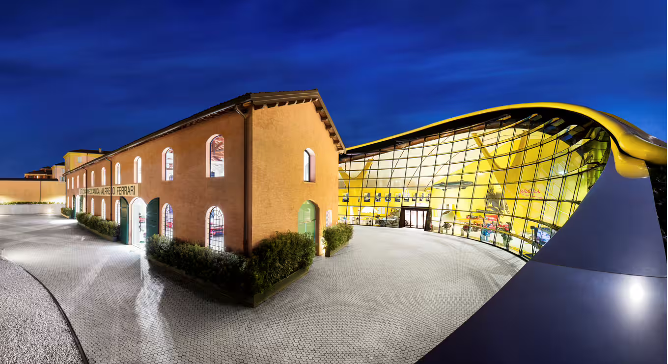Enzo Ferrari Museum Modena exterior at dusk, iconic yellow glass pavilion for Bologna entry ticket tour