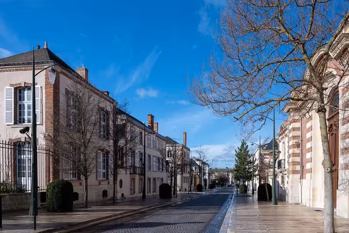 Tree-lined cobblestone street in Epernay, France, flanked by classic French architecture on a clear sunny day