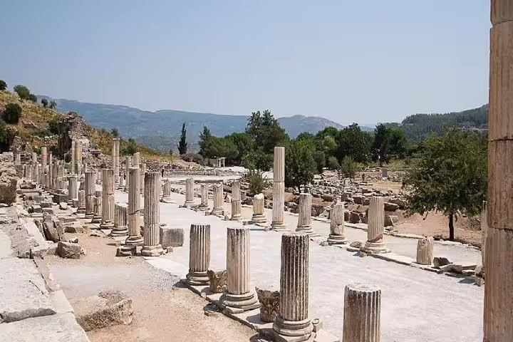 Ancient columns and ruins at Ephesus under a clear blue sky, perfect for a cultural half-day tour from Kusadasi.
