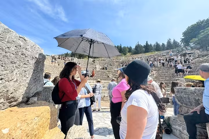 Guide with umbrella leading visitors at Ephesus ancient theater on Izmir hotel pickup Ephesus day tour