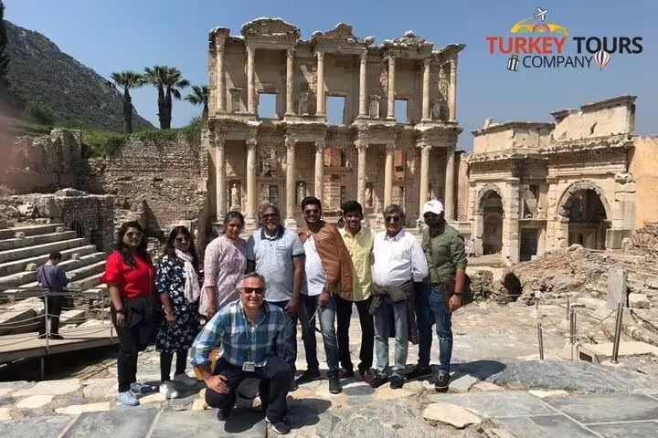 Tourists posing in front of the iconic Celsus Library during a half-day sightseeing tour from Kusadasi or Selcuk hotels.