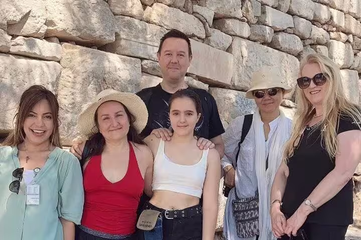 Group of tourists enjoying their Ephesus day tour from Istanbul, standing against ancient stone ruins.
