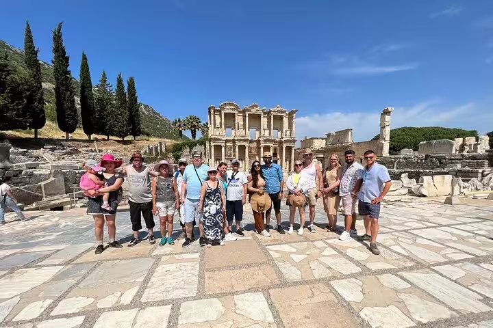 Group tour exploring ancient Ephesus ruins with Celsus Library backdrop on half-day trip from Kusadasi/Selcuk hotels.