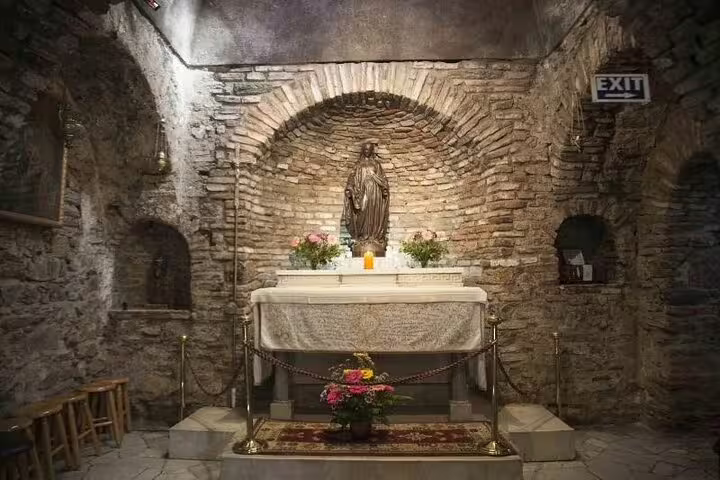 Visit the serene interior of the House of Virgin Mary near Ephesus, featuring a revered statue and rustic stone walls.