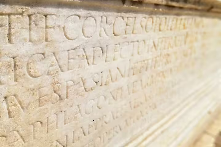 Close-up of ancient Latin inscription stone at Ephesus, featured on a full-day mini-group tour from Izmir