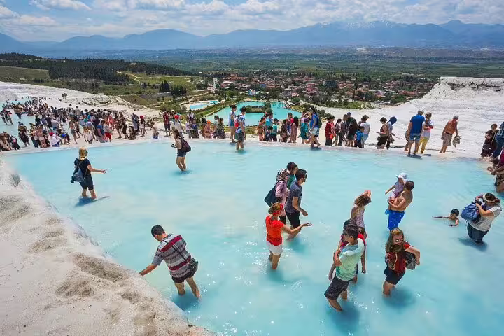 Travelers wading in Pamukkale travertine pools on a 2-day mini group Ephesus and Pamukkale tour from Kusadasi