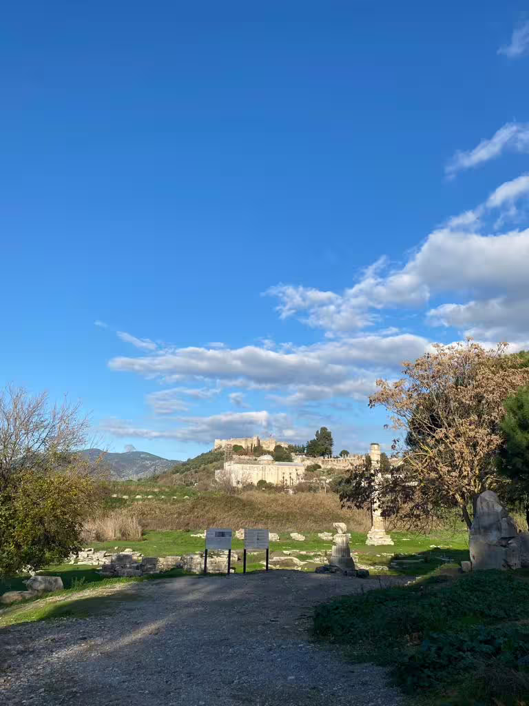 Scenic approach to ancient Ephesus ruins on private all-inclusive tour, with blue sky and hillside views