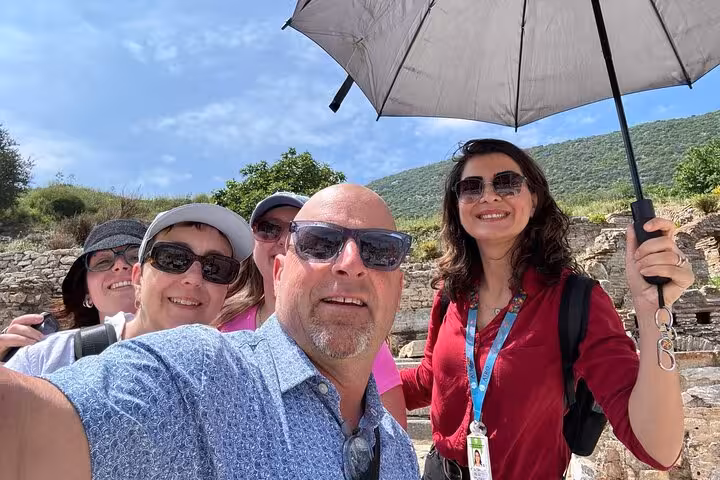 Guided Ephesus tour group selfie with umbrella at ancient ruins, on 8-day Cappadocia Pamukkale Antalya tour