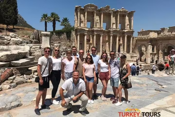 Large tour group gathered in front of the iconic Library of Celsus in Ephesus, enjoying a sunny day.
