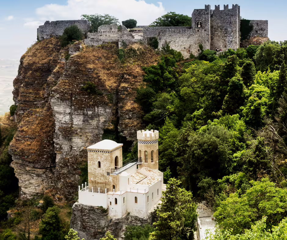 Panoramic view of Erice castle and towers on a rocky hill above lush forest, visited on private tour from Palermo