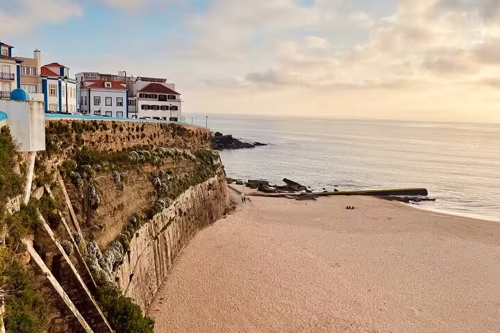 Scenic view of Ericeira's coastal cliffs and sandy beach at sunset, part of the Lisboa full-day tour to Mafra and Queluz.