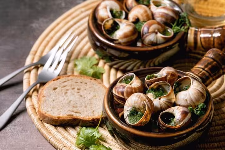 Escargots with garlic parsley butter and bread, classic French dinner on Montmartre cabaret tour Paris