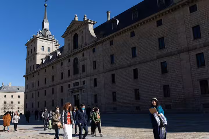 Visitors walking across El Escorial courtyard during a guided private minivan tour from Madrid, Spain