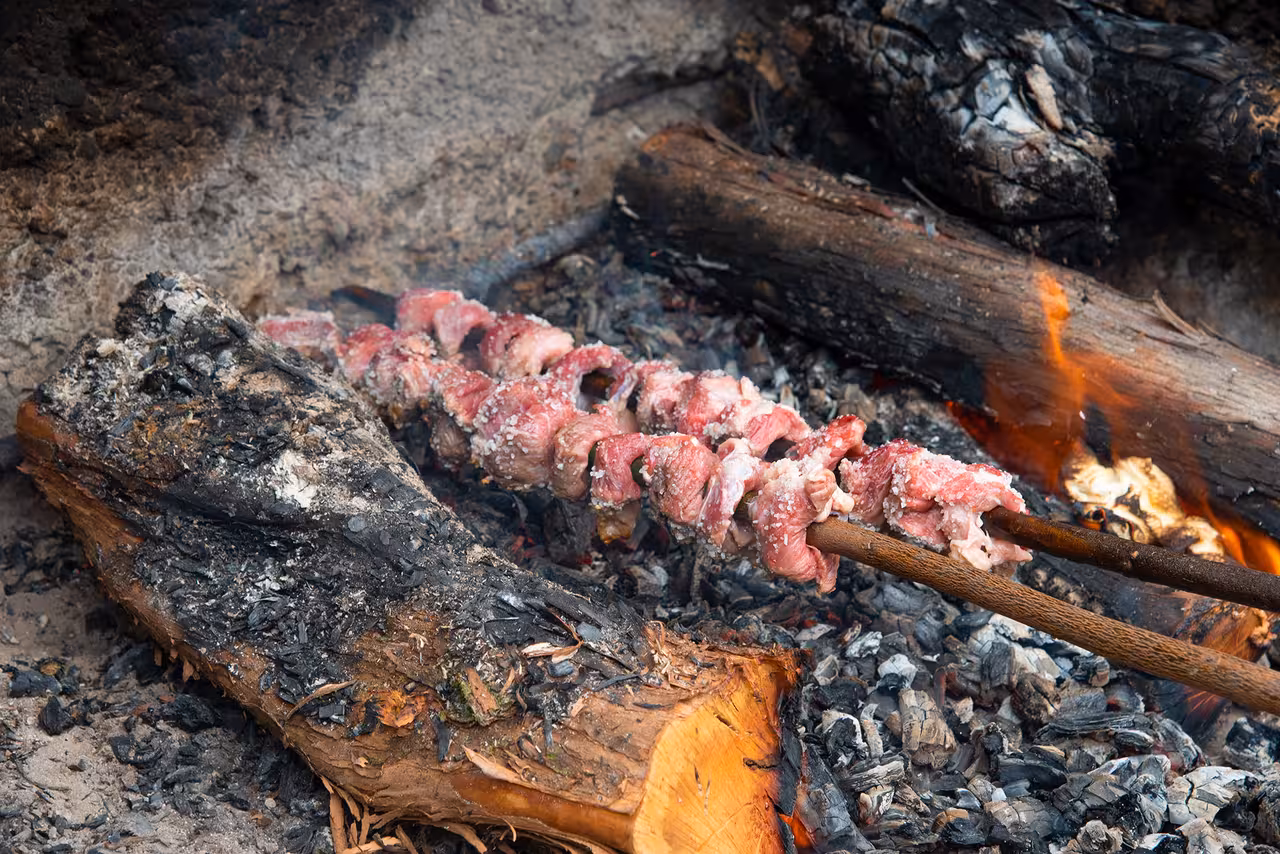 Traditional espetada skewers roasting over open fire in Madeira, showcasing authentic Portuguese culinary experience.