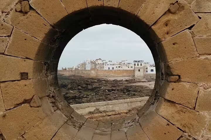 View of Essaouira medina through a stone arch, coastal ramparts stop on Marrakech to Essaouira day trip