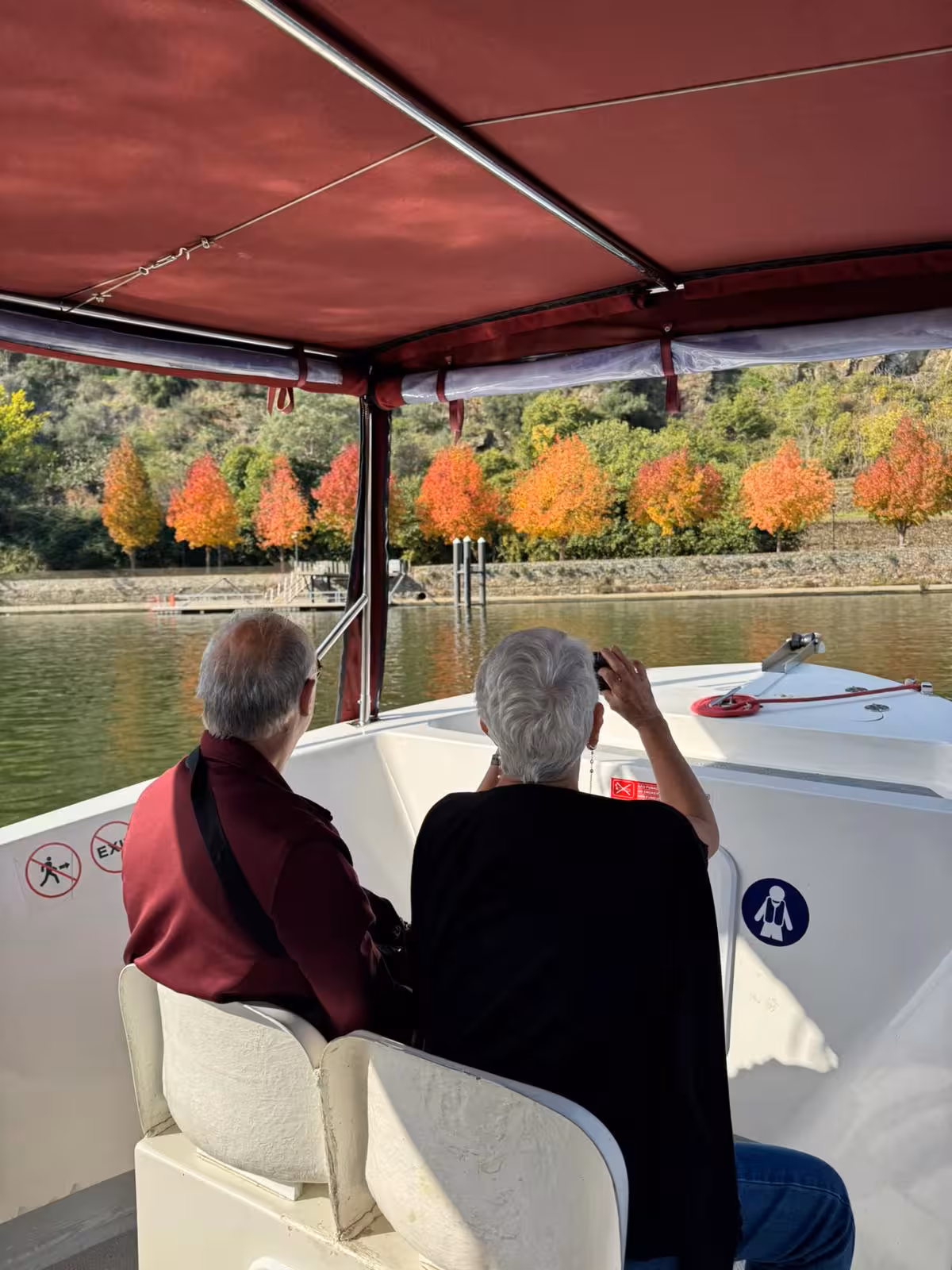 Guests on Douro River cruise boat viewing colorful autumn vineyards, a scenic experience on the Essence Tour