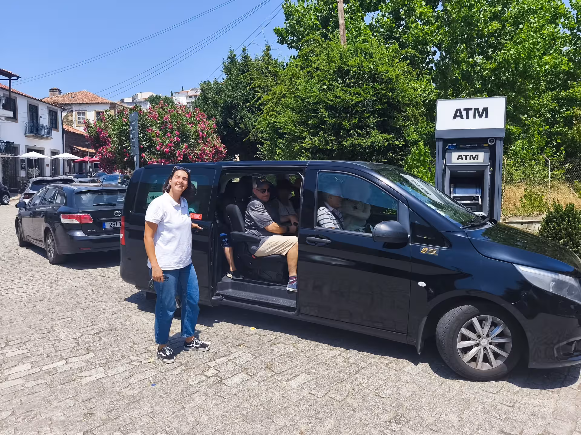 Essence Tour pickup with local guide beside private minivan in a charming village street for day trip transfers