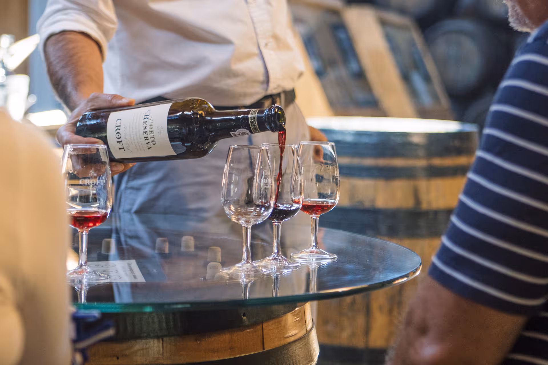 Port wine tasting on Essence Tour, red wine poured into glasses beside oak barrels in a Douro cellar