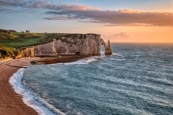 Étretat white chalk cliffs and natural arch at sunset along Normandy coastline, France