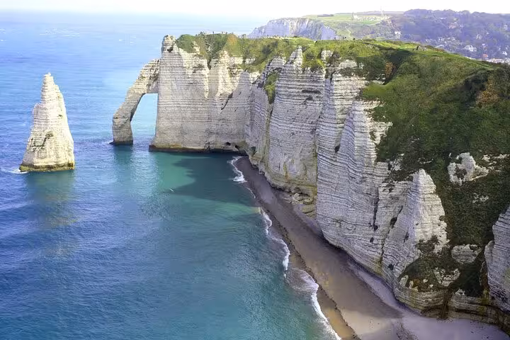 Dramatic white chalk cliffs and natural arch at Etretat with turquoise sea and pebble beach below