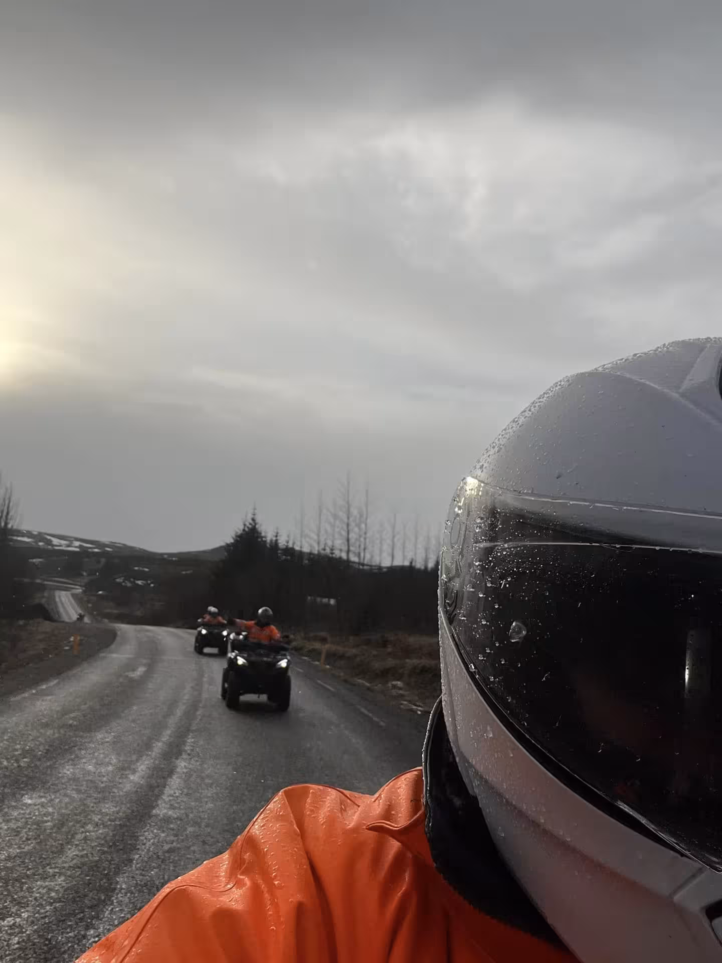ATV quad riders in orange gear on wet road at sunset in Reykjavik wilderness