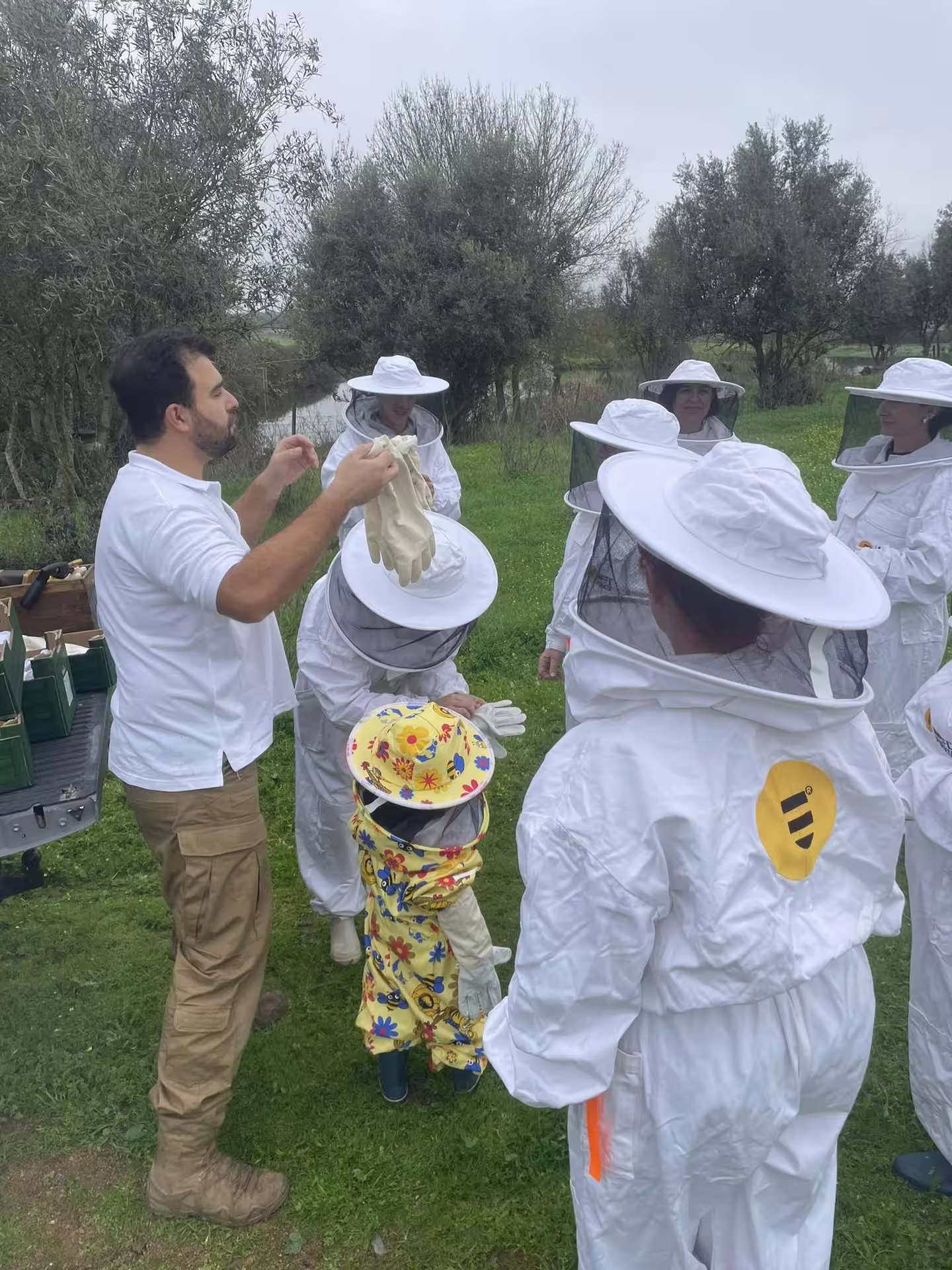 Group in beekeeping suits at Évora tour, learning about beekeeping amidst lush greenery.