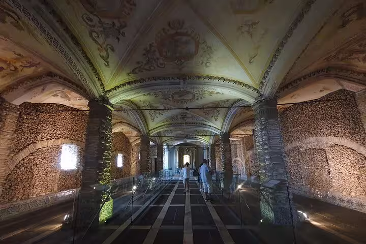 Interior view of the Capela dos Ossos in Évora with its ornate ceiling and walls lined with human bones, a highlight of the Evora & Monsaraz Private Full-Day Tour from Lisboa.