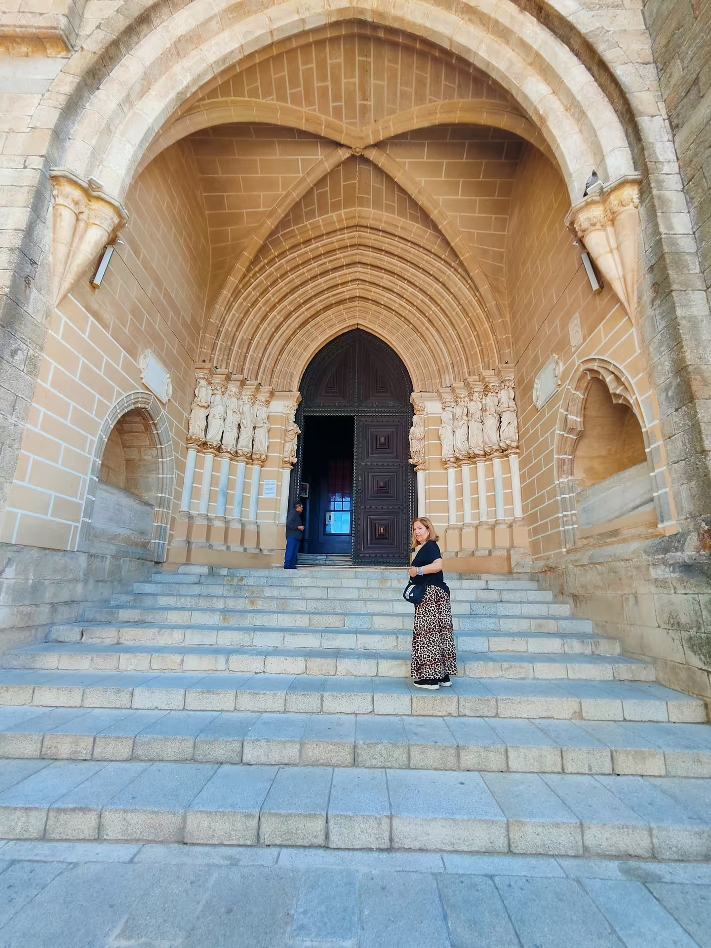 Tourist stands on the steps of Évora Cathedral, a stunning example of Gothic architecture in Portugal.