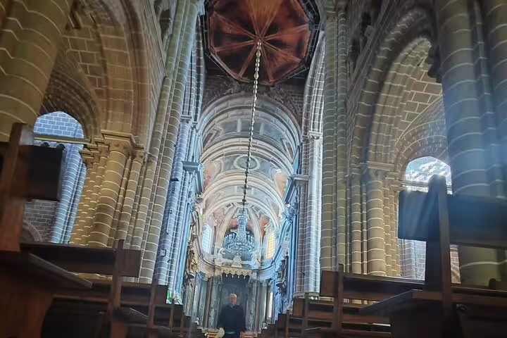 Majestic interior of Évora Cathedral, featuring stunning arches and a beautifully decorated altar under a domed ceiling.