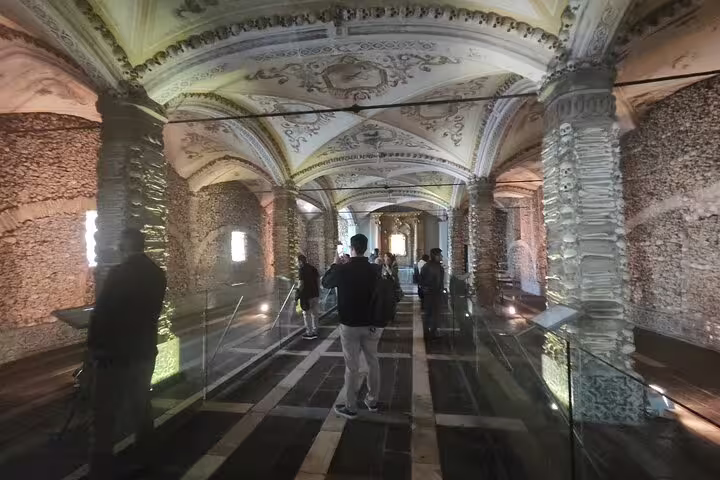 Tourists inside Évora's Chapel of Bones, admiring its eerie yet fascinating bone-adorned walls and vaulted ceilings.