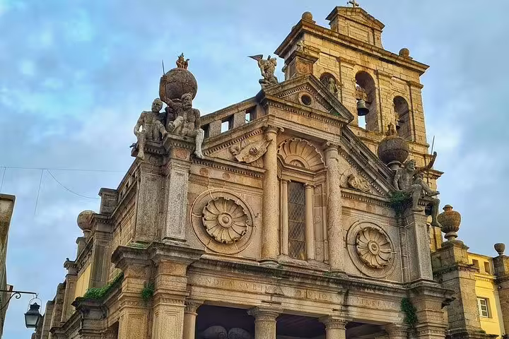 Historic stone architecture of a church in Évora, Portugal, showcasing intricate designs on a sunny day during a full-day tour from Lisbon.