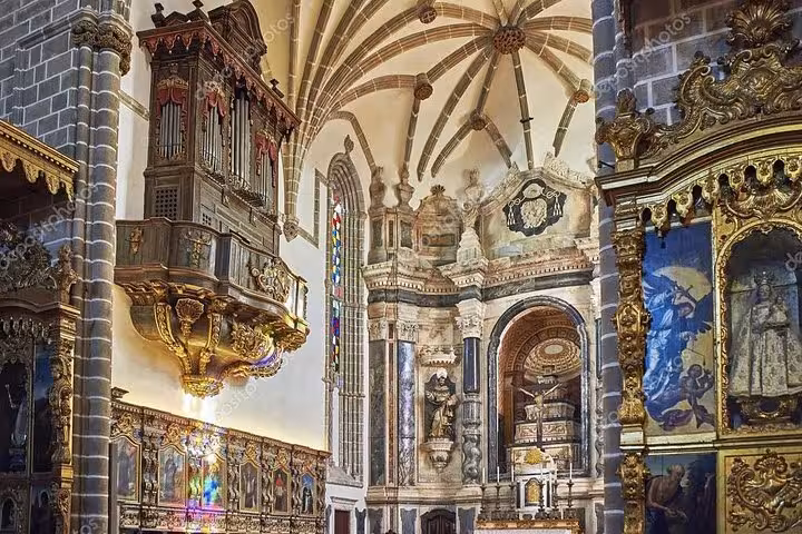 Intricate interior of a historical church in Évora featuring ornate decorations and colorful stained glass windows.