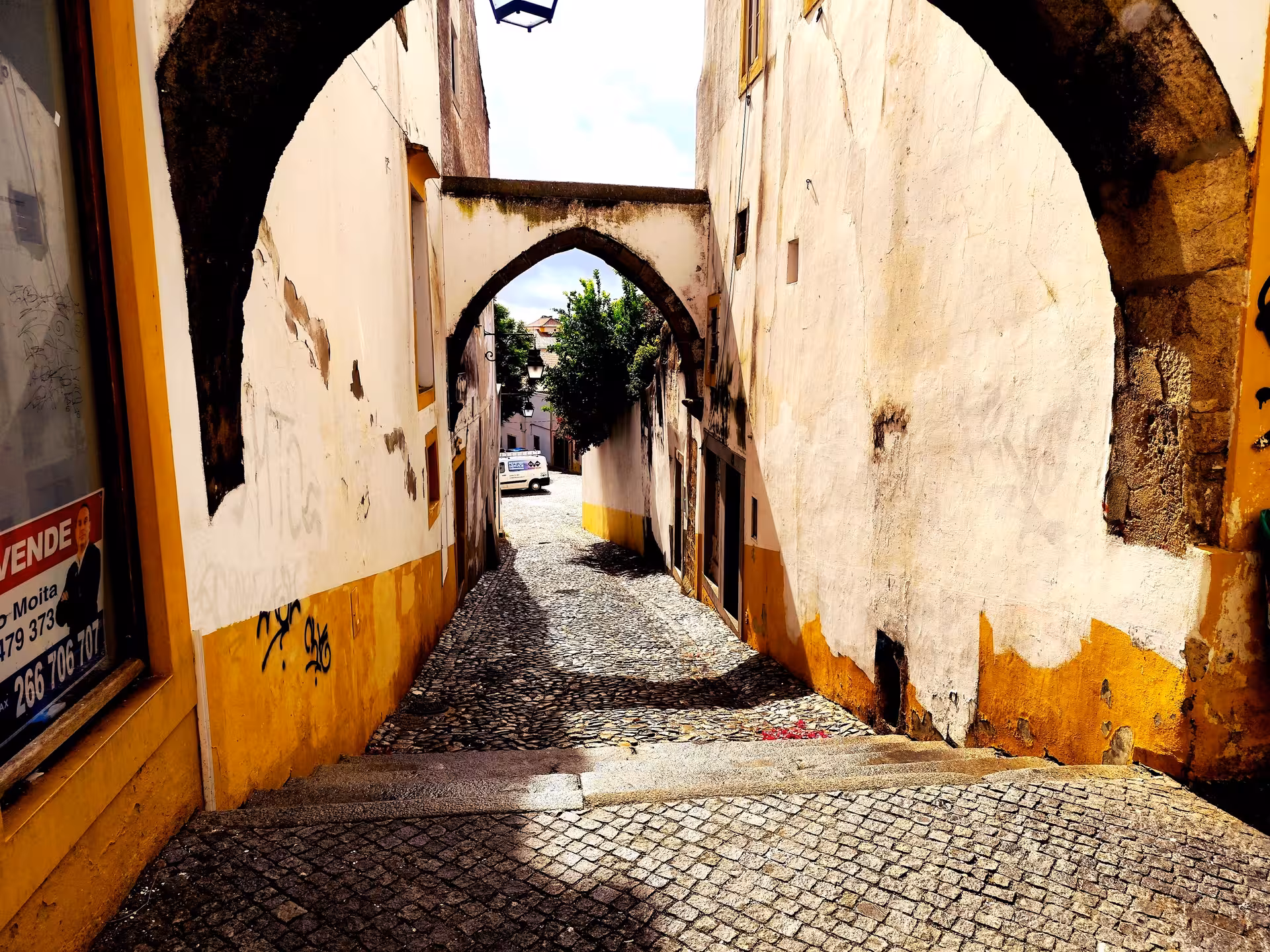 Cobbled alley under medieval arch in Évora old town, Alentejo, Portugal, on a guided walking tour