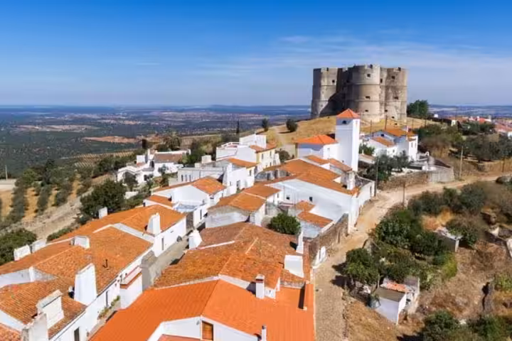 Aerial view of Évora Monte Castle towering over whitewashed village with terracotta roofs in Alentejo Portugal