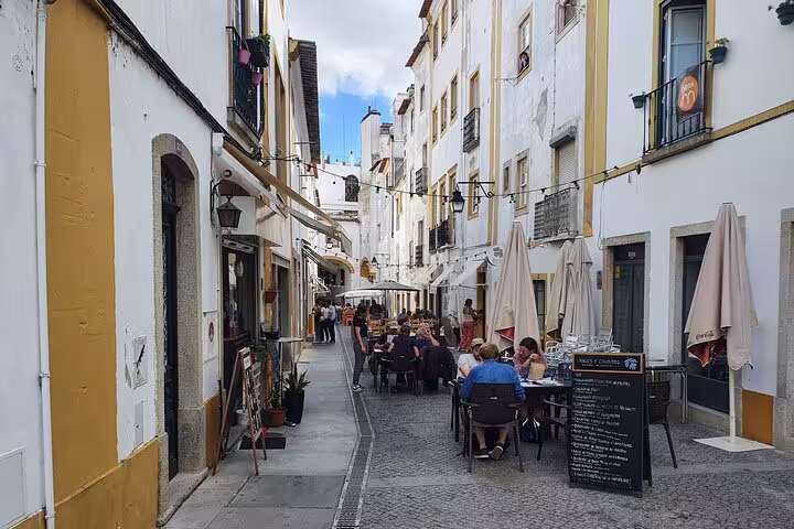 Charming narrow street in Évora with outdoor dining, showcasing local architecture and vibrant culture on a full-day private tour.