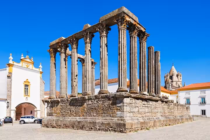 Historic Roman Temple of Évora with grand columns against a vibrant blue sky, a highlight of the private tour.