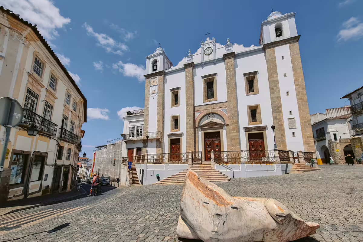 Historic white church with twin towers in Évora, Portugal, under a clear blue sky, perfect for cultural exploration.