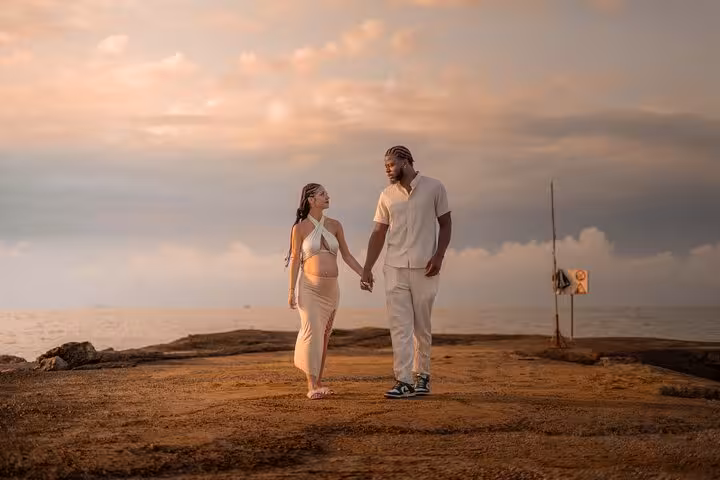 Expectant couple holding hands on a scenic Gouves pier at sunset, enjoying a private photoshoot experience.
