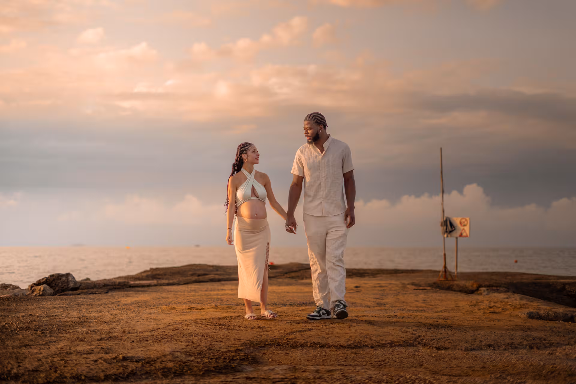 Expecting couple walking hand in hand at Heraklion Venetian Port, capturing a serene anniversary moment.