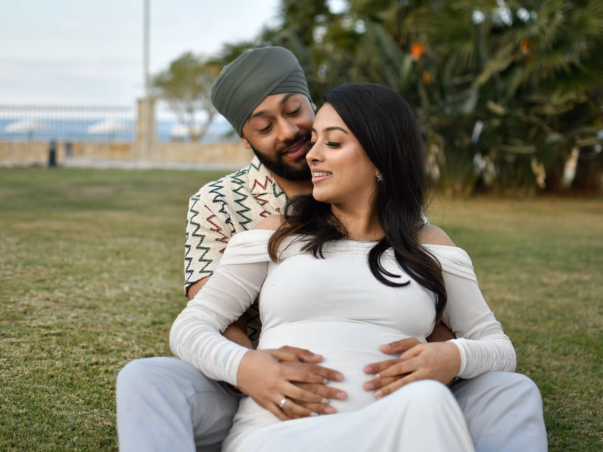 Expecting couple sharing a tender moment in a Heraklion park, perfect for a memorable maternity photoshoot.