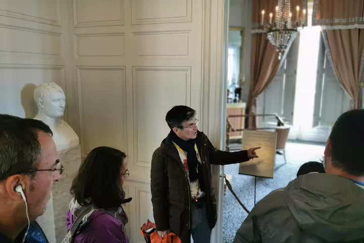 Expert guide explaining Versailles Palace interiors on a private day tour from Paris, near statue and grand doorway