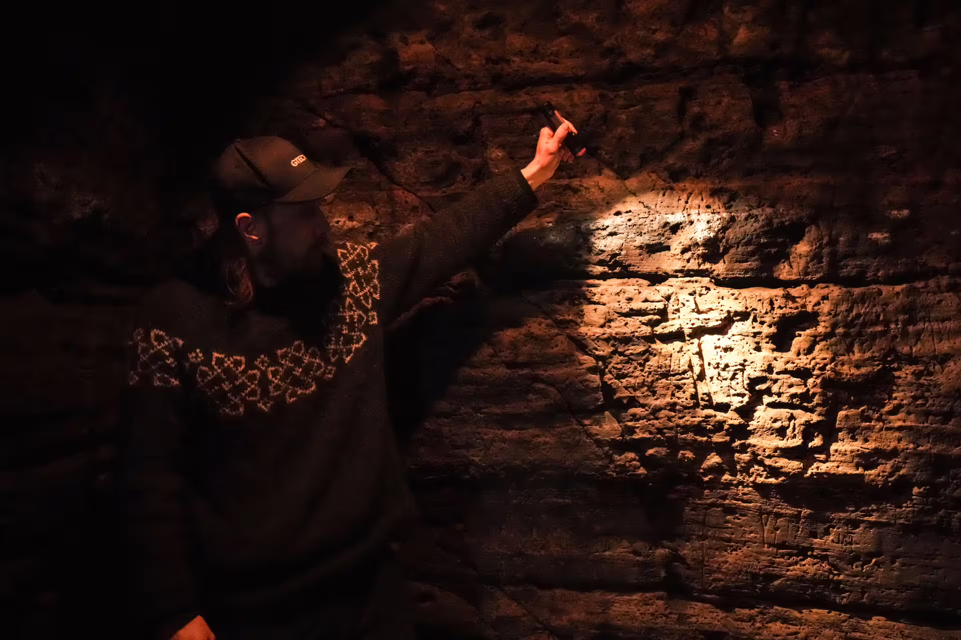 Explorer illuminating ancient Celtic stone wall with flashlight during an immersive Viking and Celtic heritage tour