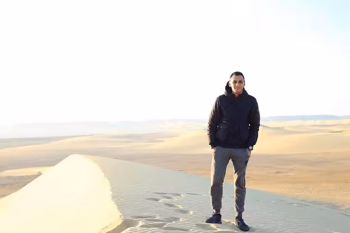 Explorer standing atop a sand dune in the vast desert of Fayoum Oasis during a private Jeep tour.