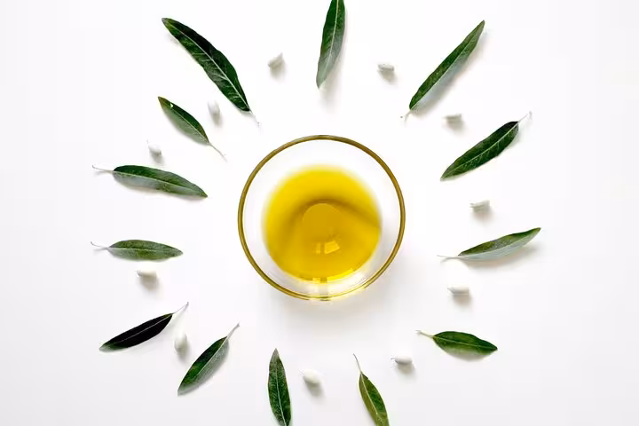 Extra virgin olive oil with olive leaves flat lay, key ingredient in Greek cooking class with Santorini caldera views
