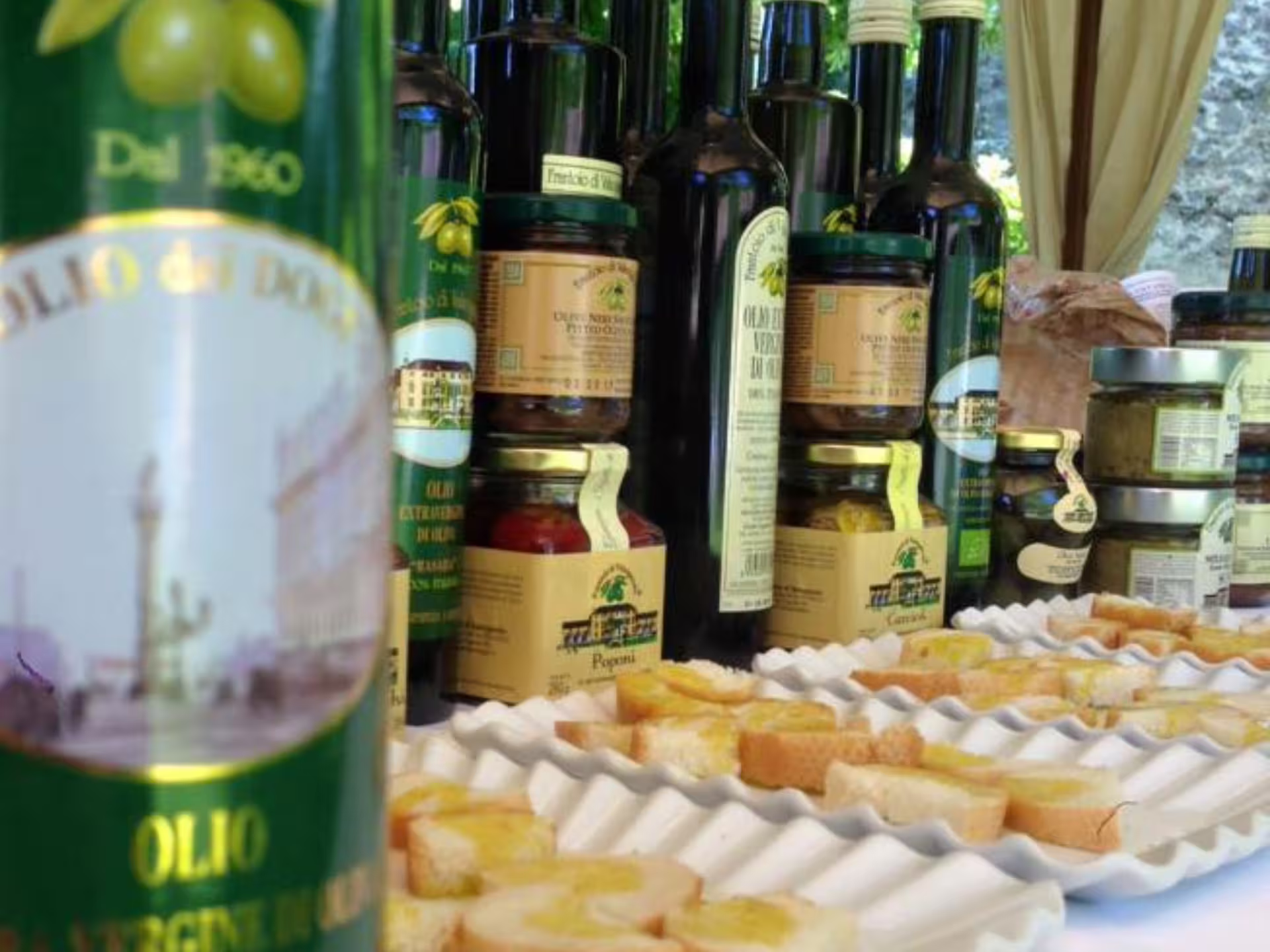 Extra virgin olive oil bottles and crostini tasting table at Padua Hills olive mill tour in Italy