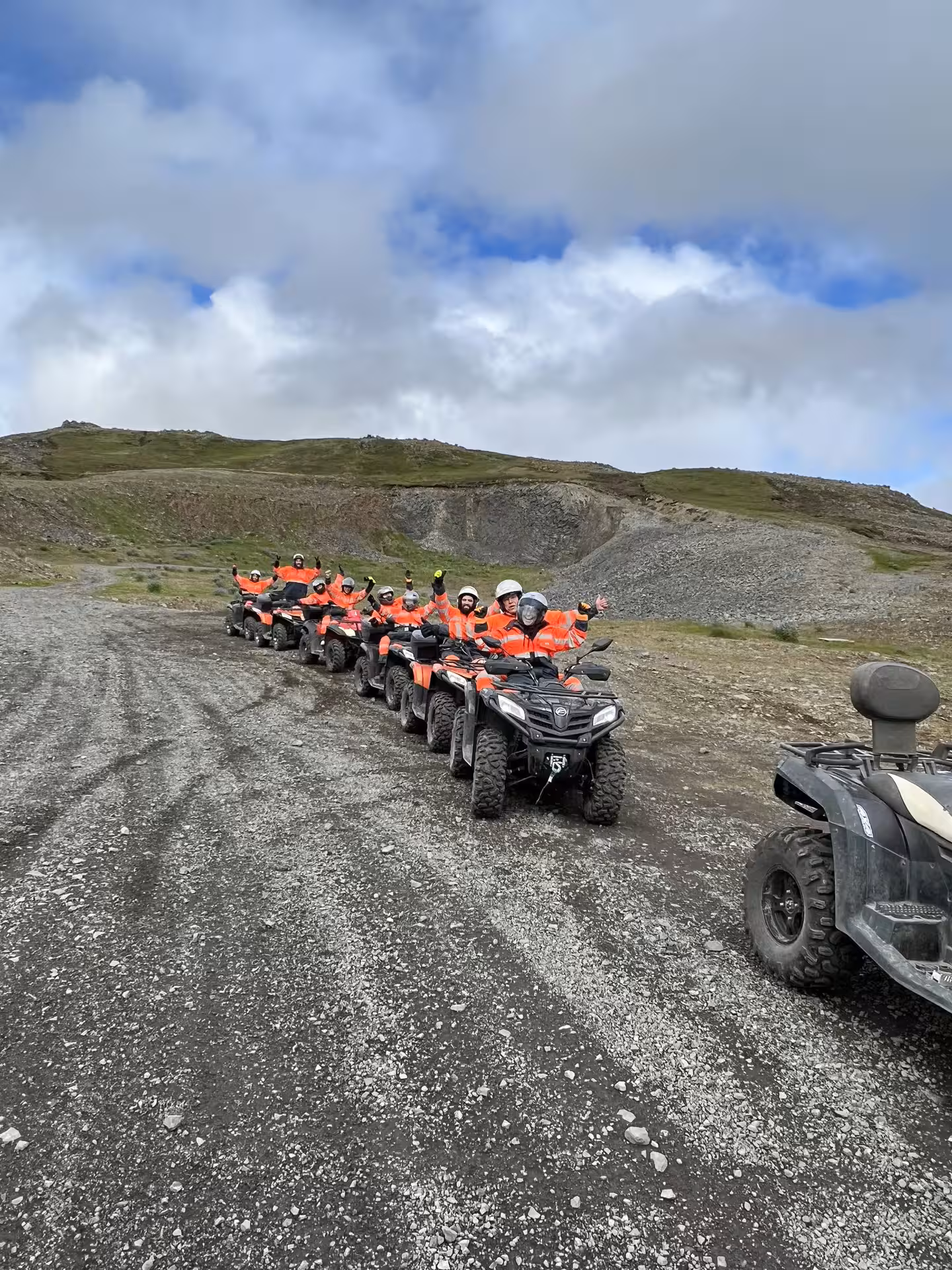 Group of riders in orange gear on ATVs lined up on rocky terrain in Reykjavik highlands